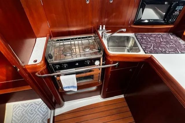 Slide: The Image of Interior of 2006 Beneteau 343 Sloop showing kitchen with stove, sink, and wooden cabinetry. - 10