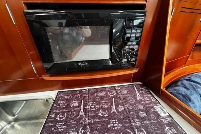 Slide: The Image of Microwave in 2006 Beneteau 343 Sloop kitchen with patterned countertop and wooden cabinetry. - 12