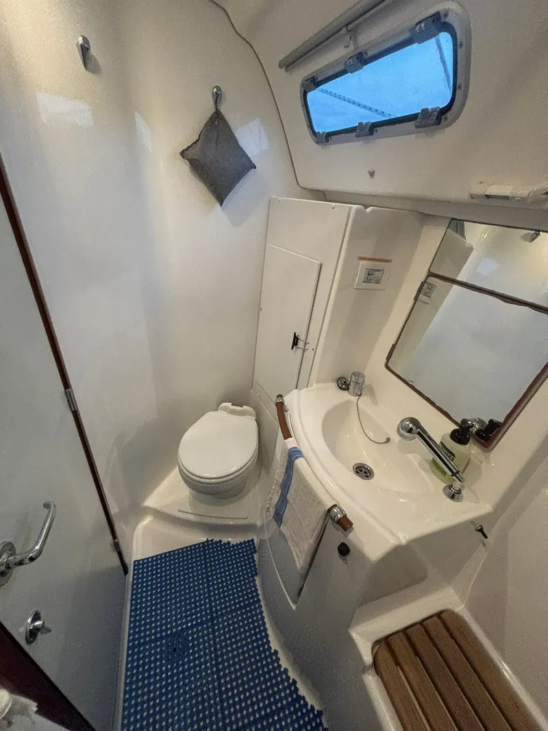Slide: The Image of 2006 Beneteau 343 Sloop bathroom with toilet, sink, mirror, and blue mat. - 19