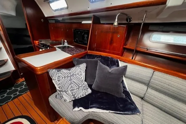 Slide: The Image of 2006 Beneteau 343 Sloop interior with cozy seating, cushions, and wooden cabinetry. - 2