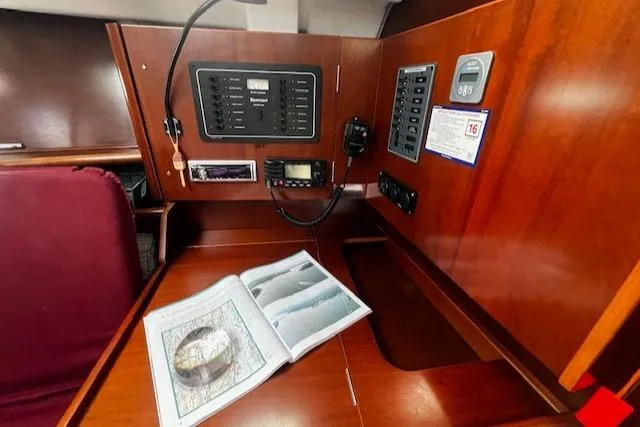 Slide: The Image of Navigation station inside 2006 Beneteau 343 Sloop with control panels and open map book. - 24