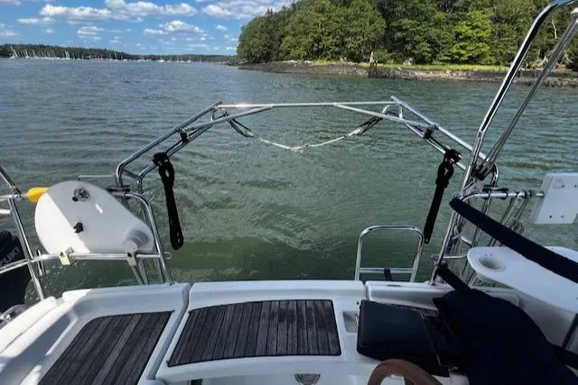 Slide: The Image of 2006 Beneteau 343 Sloop sailboat on calm water, with lush green shoreline in the background. - 38