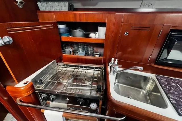 Slide: The Image of 2006 Beneteau 343 Sloop kitchen with stove, sink, and wooden cabinetry. - 8