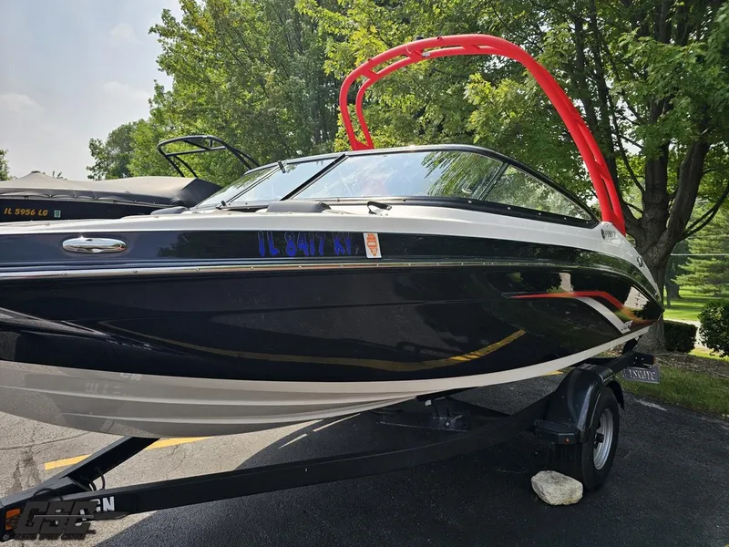 Slide: The Image of 2019 Yamaha AR195 boat with red tower, parked on a trailer, surrounded by trees. - 19