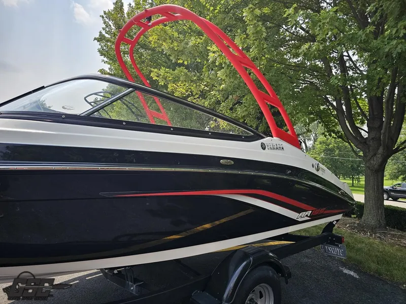 Slide: The Image of 2019 Yamaha AR195 boat with red accents, parked near trees. - 20