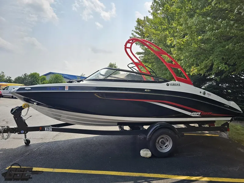 Slide: The Image of 2019 Yamaha AR195 boat on trailer, black and white with red accents, parked outdoors. - 21