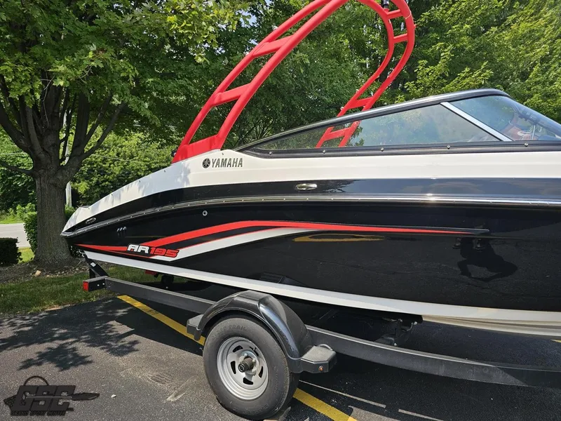 Slide: The Image of 2019 Yamaha AR195 boat with red accents on a trailer, parked near trees. - 3
