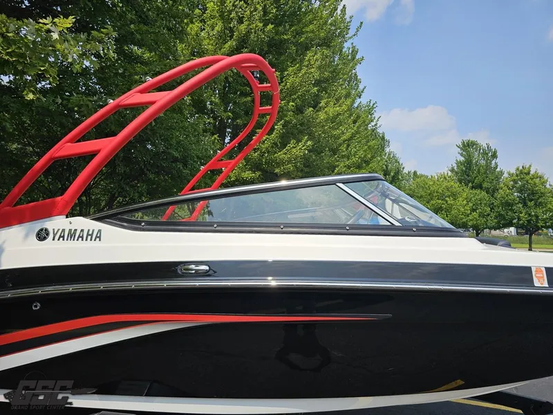 Slide: The Image of 2019 Yamaha AR195 boat with red wakeboard tower, parked near lush green trees. - 5