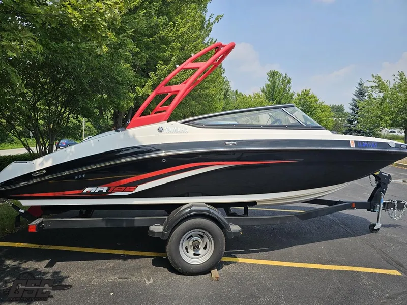 Slide: The Image of 2019 Yamaha AR195 boat with red accents on a trailer, parked outdoors. - 8