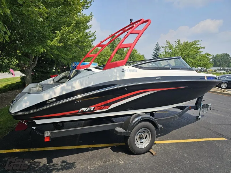 Slide: The Image of 2019 Yamaha AR195 boat on trailer, parked outdoors with trees in background. - 9