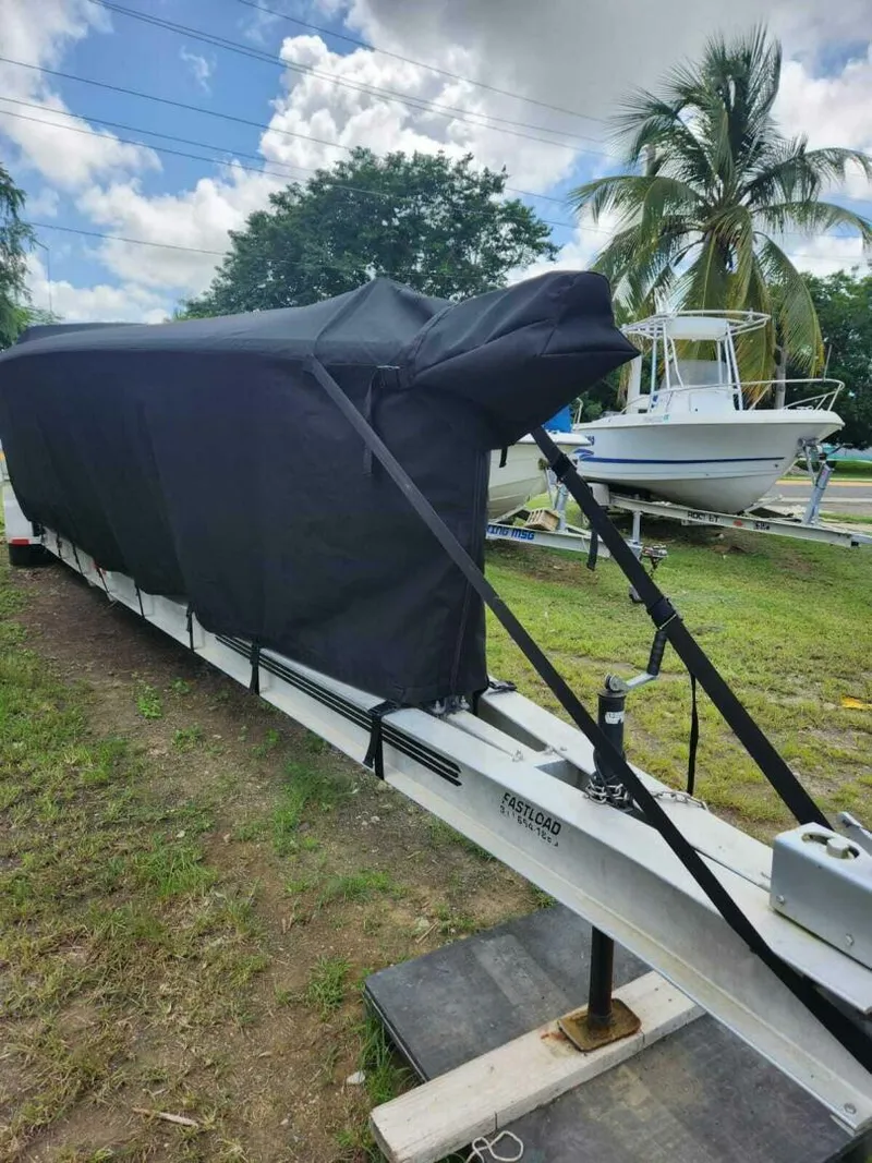 Slide: The Image of 1996 Wellcraft SCARAB boat covered on trailer, parked outdoors near palm tree. - 27
