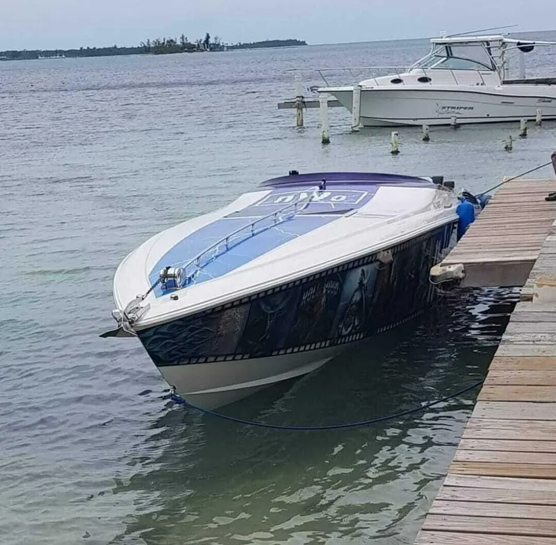Slide: The Image of 1996 Wellcraft SCARAB speedboat docked by the shore, with a scenic ocean backdrop. - 7
