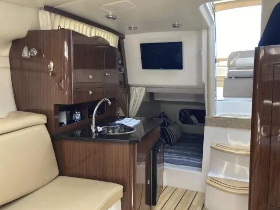 Slide: The Image of Interior of 2013 Regal 30 Express boat with kitchenette, seating, and TV. - 18