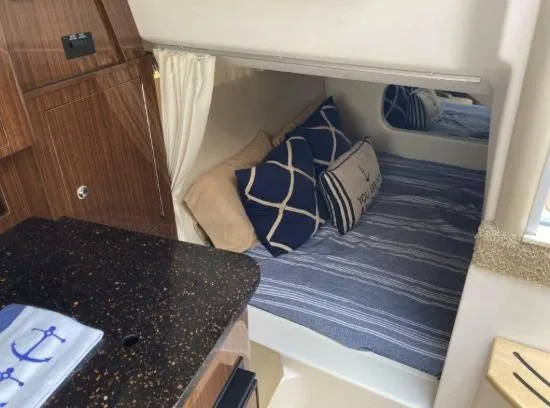 Slide: The Image of 2013 Regal 30 Express cabin with cozy bed, nautical pillows, and elegant wood cabinetry. - 22