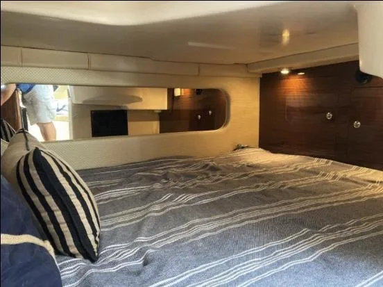 Slide: The Image of 2013 Regal 30 Express cabin interior with striped bedding and wooden accents. - 23