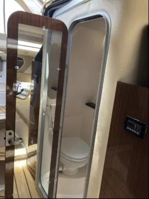 Slide: The Image of 2013 Regal 30 Express boat interior with compact bathroom and wooden accents. - 25