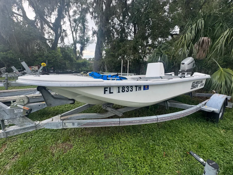 Slide: The Image of 2009 Carolina Skiff JV15CC boat on trailer, parked on grass with trees in background. - 2