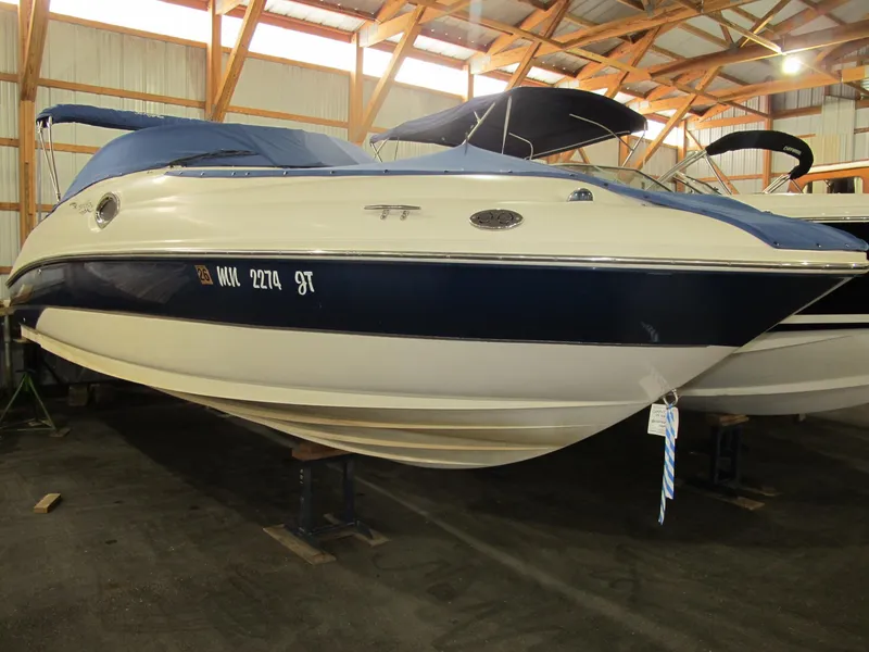 The Image of 2004 Sea Ray 240 Sundeck boat in indoor storage, blue and white exterior. - 1
