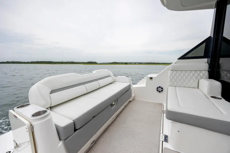 Slide: The Image of 2022 Regal 36 Grande Coupe boat interior with white seating and water view. - 15
