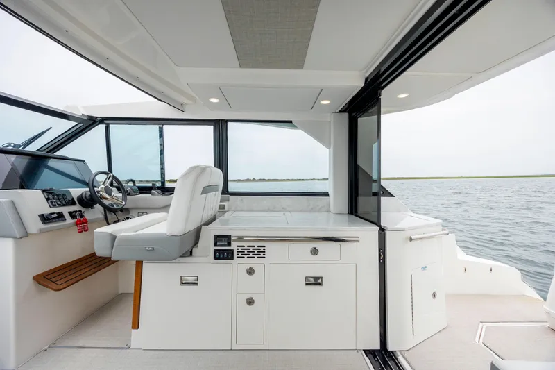 Slide: The Image of 2022 Regal 36 Grande Coupe interior with helm, seating, and water view. - 25