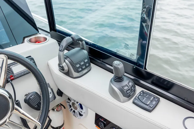 Slide: The Image of 2022 Regal 36 Grande Coupe helm controls with joystick and throttle near water. - 33