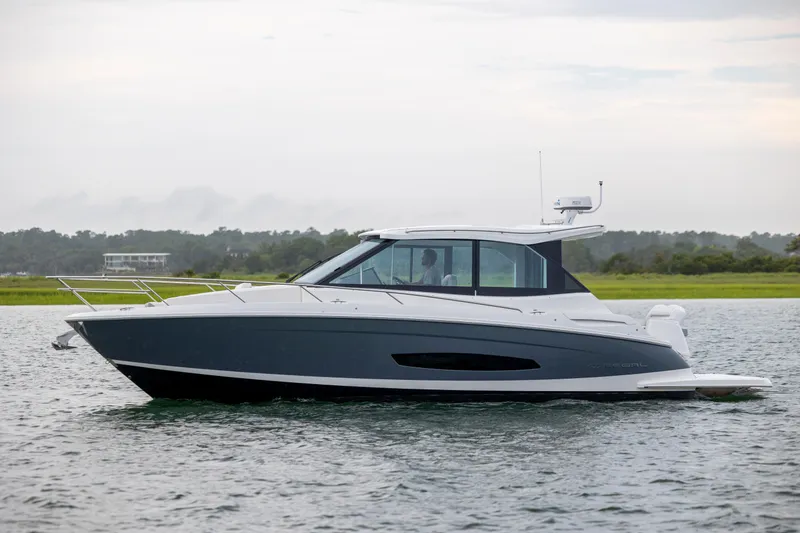 Slide: The Image of 2022 Regal 36 Grande Coupe cruising on a calm lake with a scenic backdrop. - 4