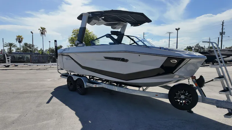 The Image of 2026 Nautique Paragon G23 boat on trailer, parked outdoors under clear sky. - 0