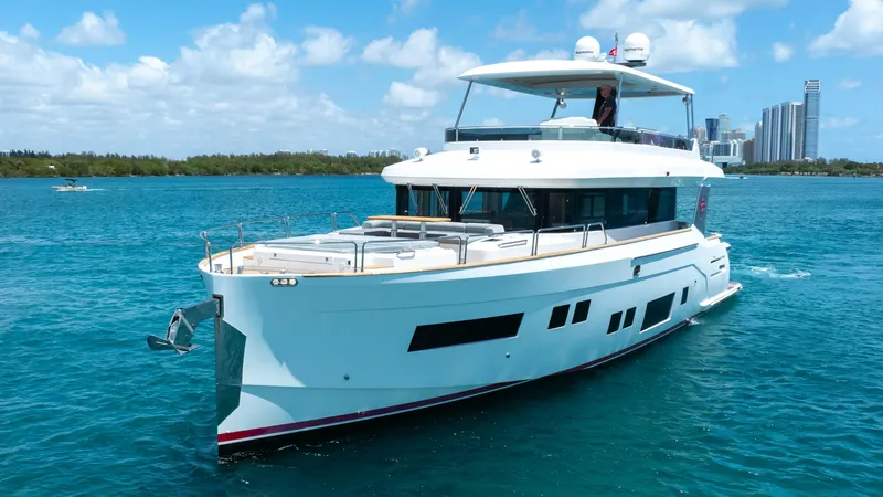 Slide: The Image of 2018 Sirena 64 yacht cruising on blue water with city skyline in the background. - 1