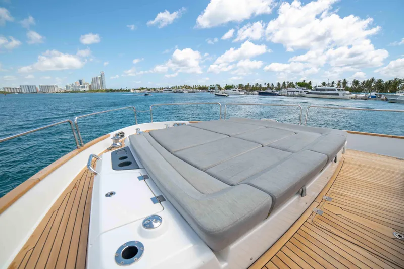 Slide: The Image of 2018 Sirena 64 yacht deck with sunbed, ocean view, and city skyline in the background. - 13