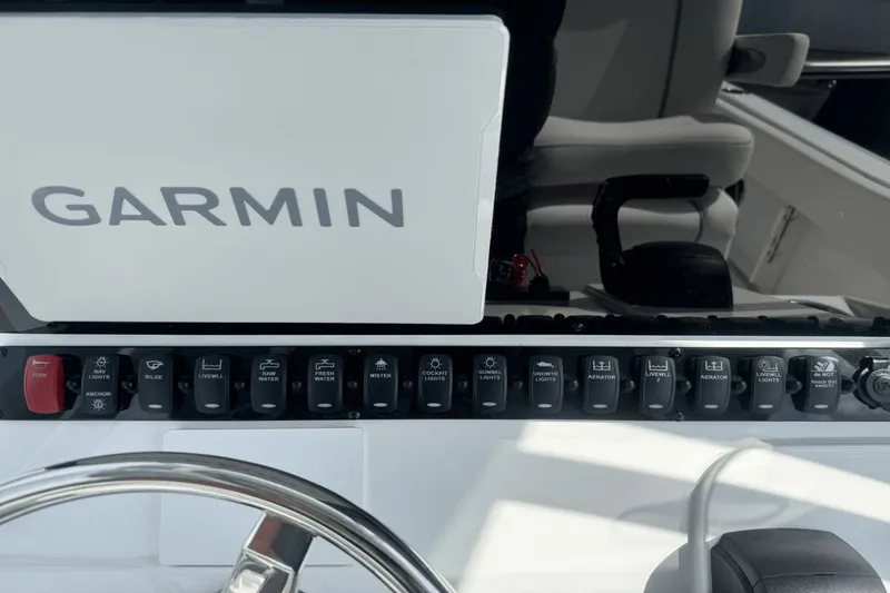 Slide: The Image of Control panel of 2023 Sea Hunt 234 Ultra boat with Garmin display and various switches. - 18