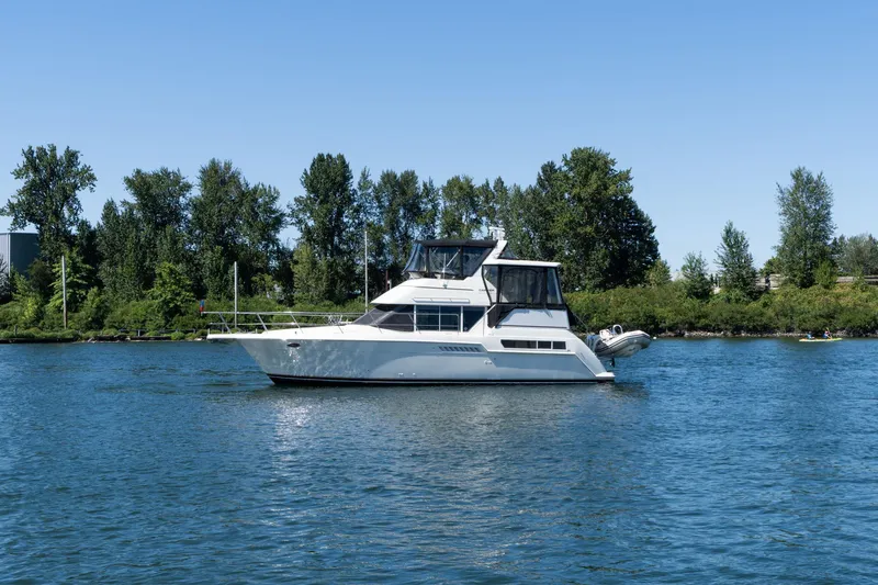 The Image of 1998 Carver 355 Aft Cabin yacht on a serene lake with lush green trees. - 0