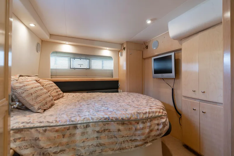 Slide: The Image of 1998 Carver 355 Aft Cabin bedroom with bed, TV, and wooden cabinetry. - 10