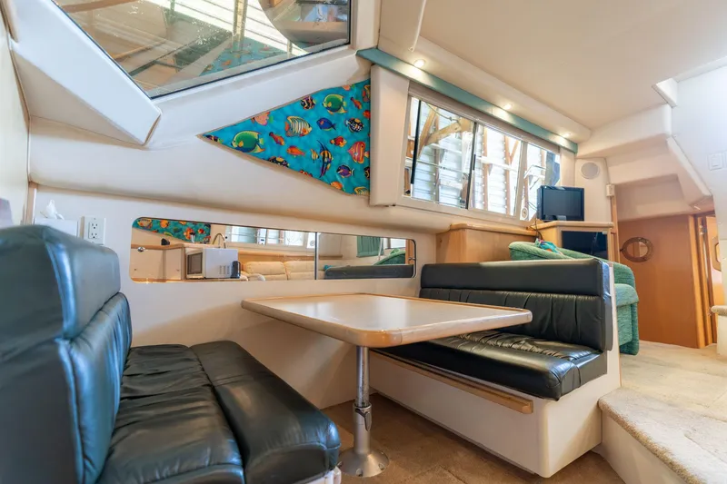 Slide: The Image of 1998 Carver 355 Aft Cabin interior with dining area, leather seating, and nautical decor. - 16