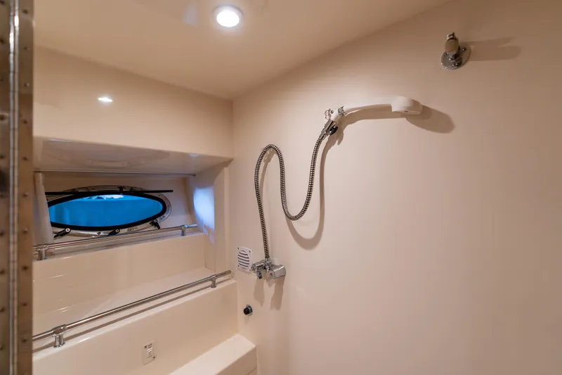 Slide: The Image of 1998 Carver 355 Aft Cabin bathroom with showerhead and porthole window. - 24