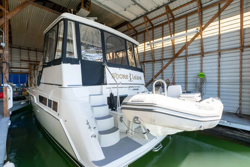 Slide: The Image of 1998 Carver 355 Aft Cabin yacht docked in a covered marina with inflatable boat. - 3
