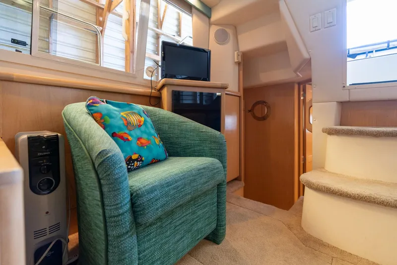 Slide: The Image of 1998 Carver 355 Aft Cabin interior with green chair, colorful pillow, and small TV. - 8