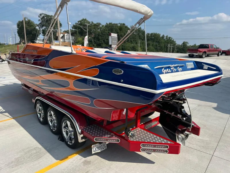 Slide: The Image of 2008 Shockwave Fundeck boat with vibrant orange and blue design on a trailer. - 2