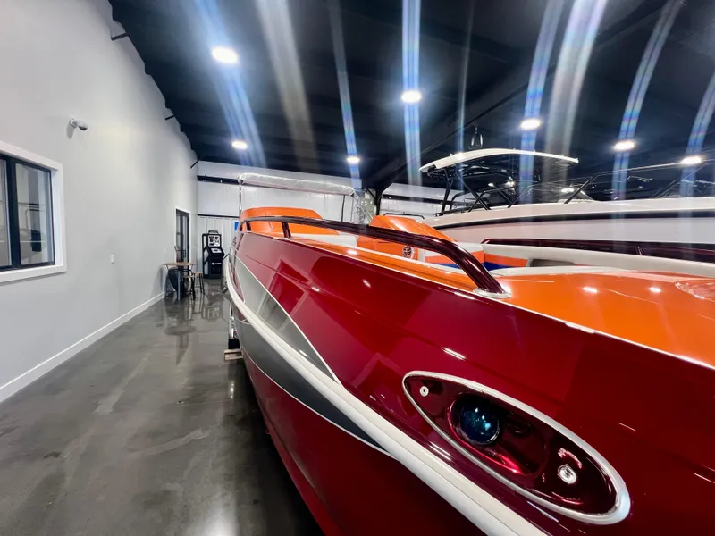 Slide: The Image of 2008 Shockwave Fundeck boat with vibrant red and orange design in a showroom. - 26