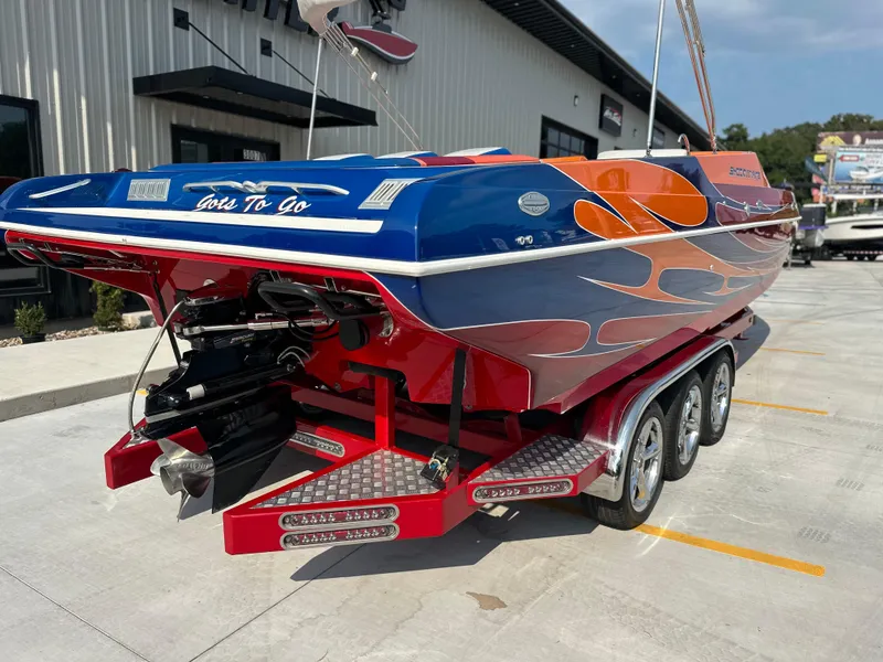 Slide: The Image of 2008 Shockwave Fundeck boat with vibrant custom paint, parked on a trailer. - 4