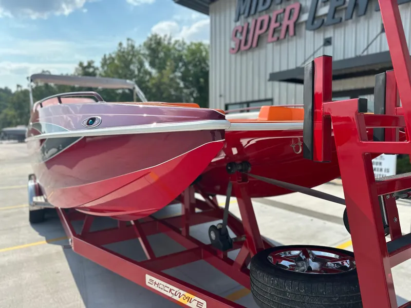 Slide: The Image of 2008 Shockwave Fundeck boat on red trailer at dealership, sunny day. - 6