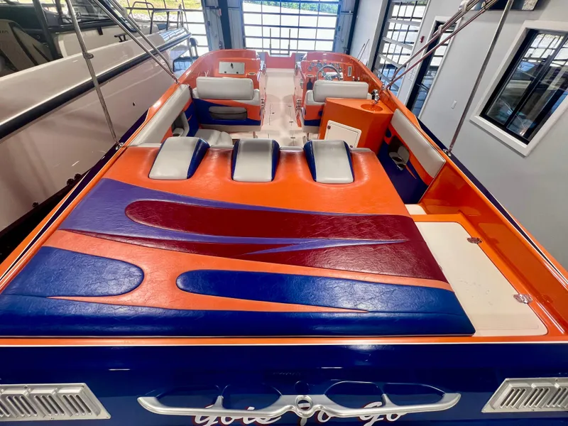 Slide: The Image of 2008 Shockwave Fundeck boat with vibrant orange and blue interior, docked indoors. - 9