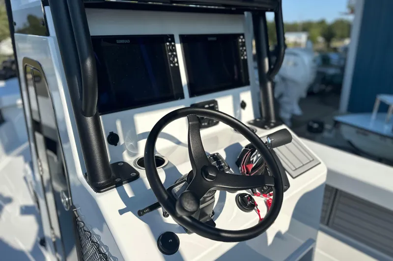 Slide: The Image of 2025 East Cape 25 Open boat dashboard with steering wheel and navigation screens. - 25