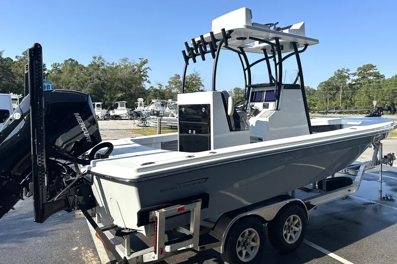 Slide: The Image of 2025 East Cape 25 Open boat on trailer, featuring Mercury engine, parked outdoors. - 30