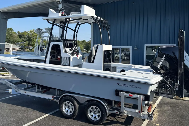 Slide: The Image of 2025 East Cape 25 Open boat on trailer, parked outside a blue building. - 39