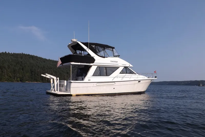 Slide: The Image of 2000 Bayliner 3988 Command Bridge Motoryacht on serene lake with forested shoreline. - 1