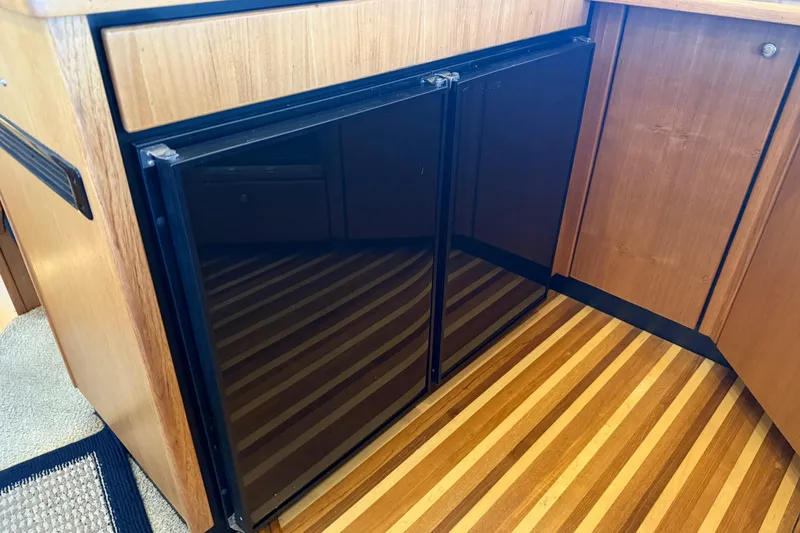 Slide: The Image of Wood-paneled kitchen area in 2000 Bayliner 3988 Command Bridge Motoryacht with black double-door fridge. - 12