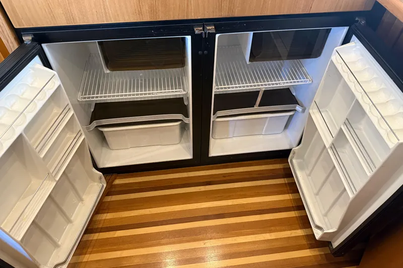 Slide: The Image of Empty refrigerator in 2000 Bayliner 3988 Command Bridge Motoryacht, featuring wooden flooring. - 13