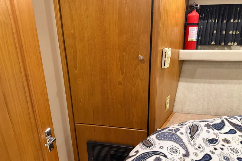 Slide: The Image of Interior of 2000 Bayliner 3988 yacht with wood paneling, fire extinguisher, and paisley bedding. - 32