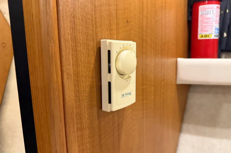 Slide: The Image of Thermostat on wooden panel inside 2000 Bayliner 3988 Command Bridge Motoryacht, with fire extinguisher nearby. - 34