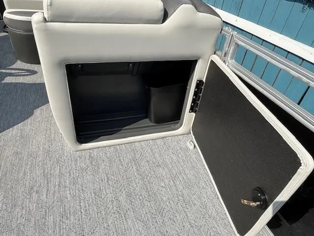Slide: The Image of 2026 Sun Tracker Fishin' Barge 20 DLX storage compartment with open door, gray interior. - 18